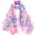 A lightweight pink scarf with a watercolor floral print in shades of blue, purple, and yellow, styled in a loose loop on a white background.
