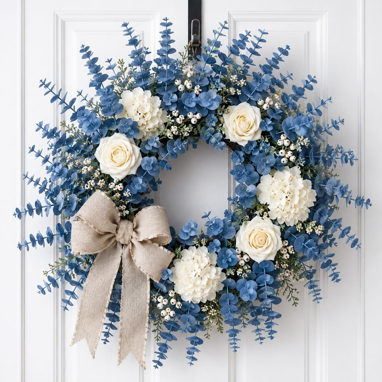 Floral wreath with blue and white flowers and a beige bow on a white door.