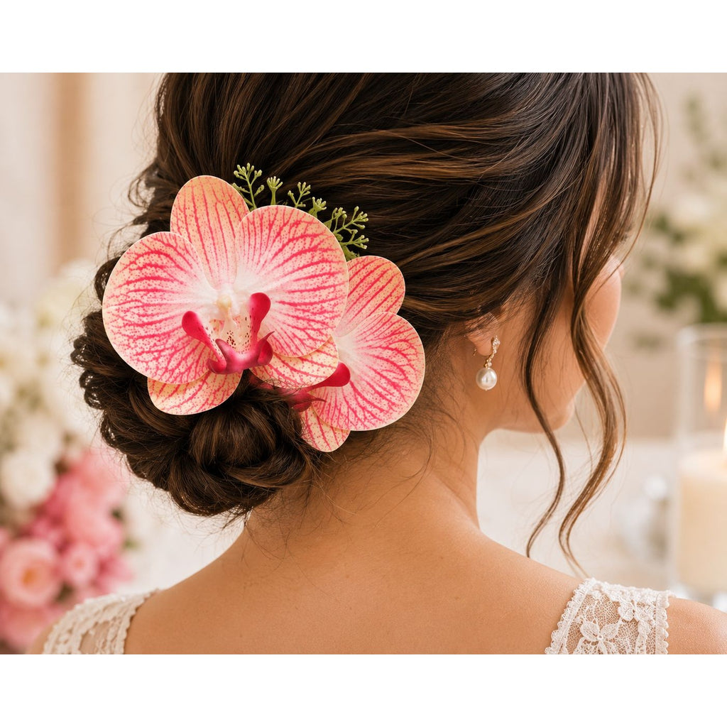 A pink and white orchid flower hair accessory styled in a woman's updo bun, shown from the back. The flower has prominent pink and white striped petals with a bright pink center and small green sprigs, worn next to a pearl drop earring.