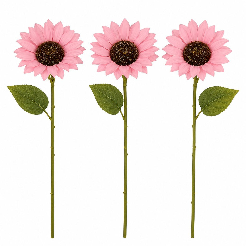 Three artificial pink sunflowers with green stems and leaves, arranged vertically on a plain white background.