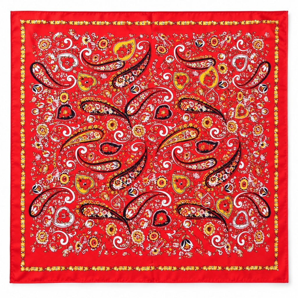 A square red satin scarf featuring an intricate paisley and floral pattern in yellow, white, black, and orange, finished with a decorative border.