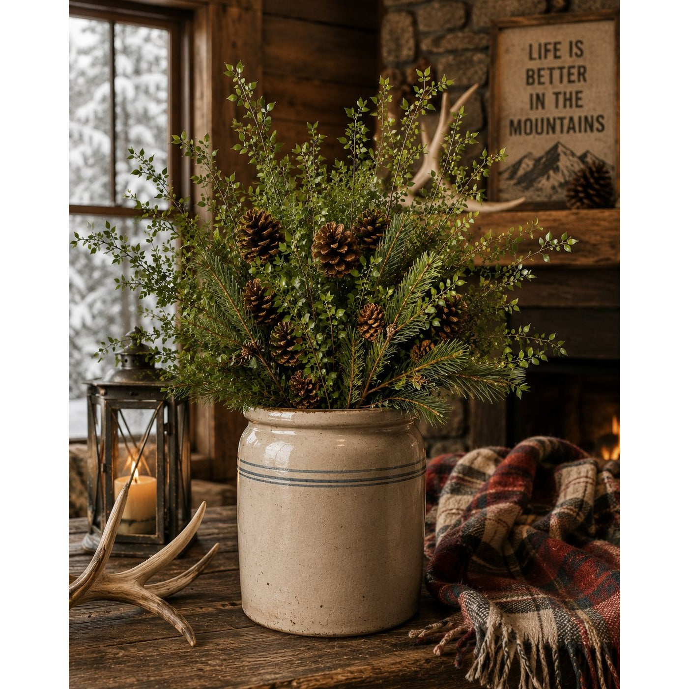 Decorative arrangement of greenery and pinecones in a rustic setting with a candle and plaid blanket.