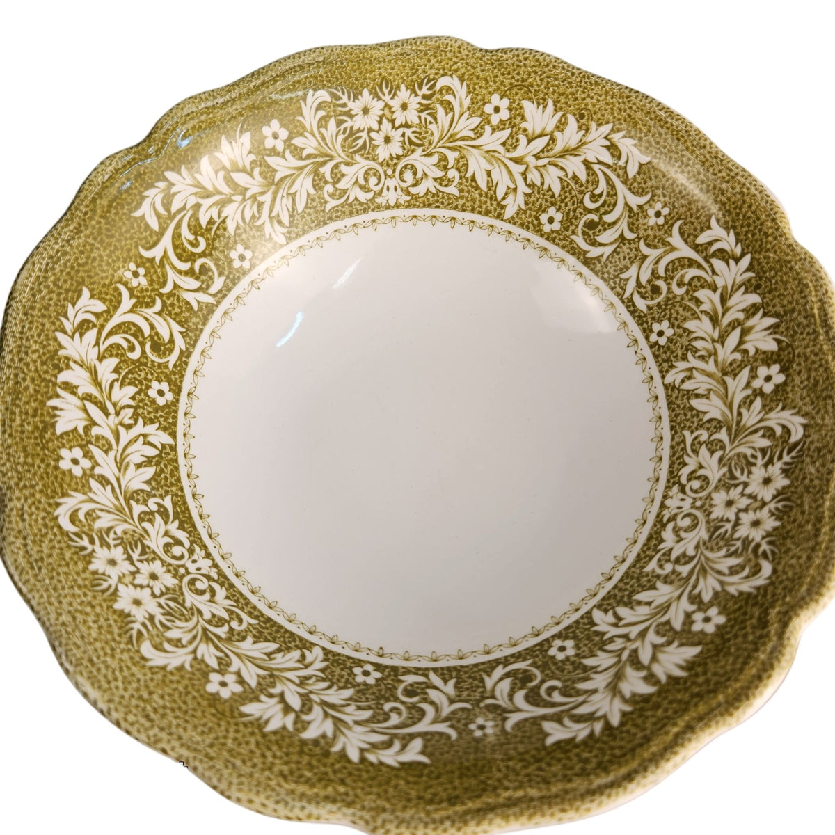 A scalloped ceramic bowl with a speckled olive green exterior and a white floral pattern around the rim, shown from a top-down view on a white background.
