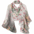 A lightweight sheer scarf draped in a loose loop, featuring a delicate watercolor floral print with pink blossoms, green leaves, and soft peach tones on a pale gray-white background.