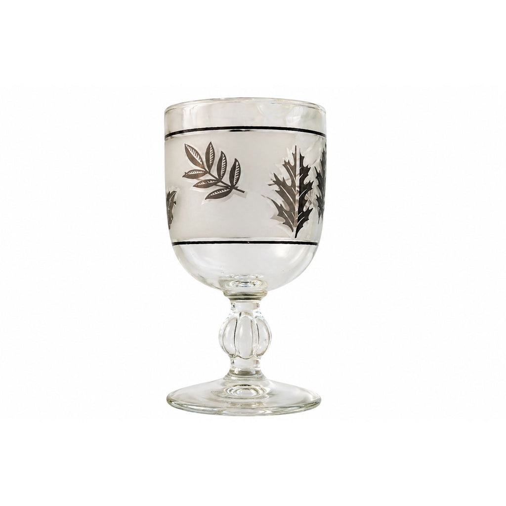 Decorative glass goblet with leaf patterns on a white background