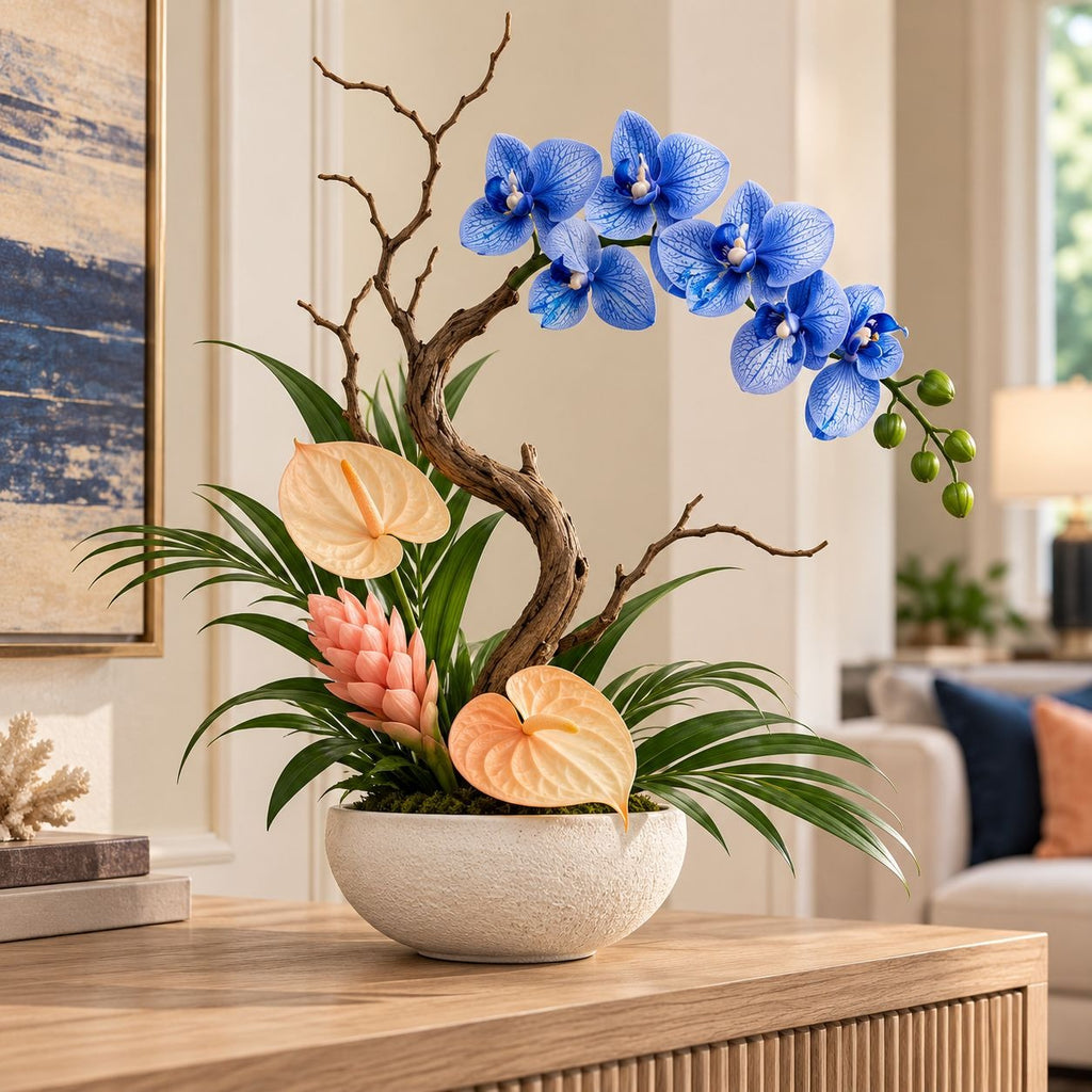 A decorative floral arrangement in a round white ceramic pot, featuring bright blue orchids, peach anthuriums, green palm fronds, and a curved brown branch, displayed on a wooden console table in a softly lit living room.