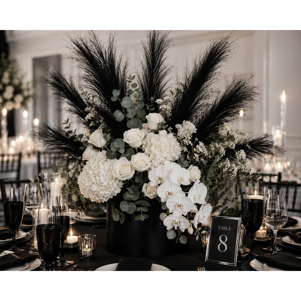 Decorative floral arrangement with black feathers and white flowers on a table setting.