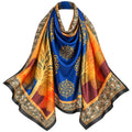 A silk-like scarf draped to display its pattern, featuring a royal blue center with gold mandala motifs, a golden tree design, and orange and burgundy sections, finished with an ornate gold and black border.