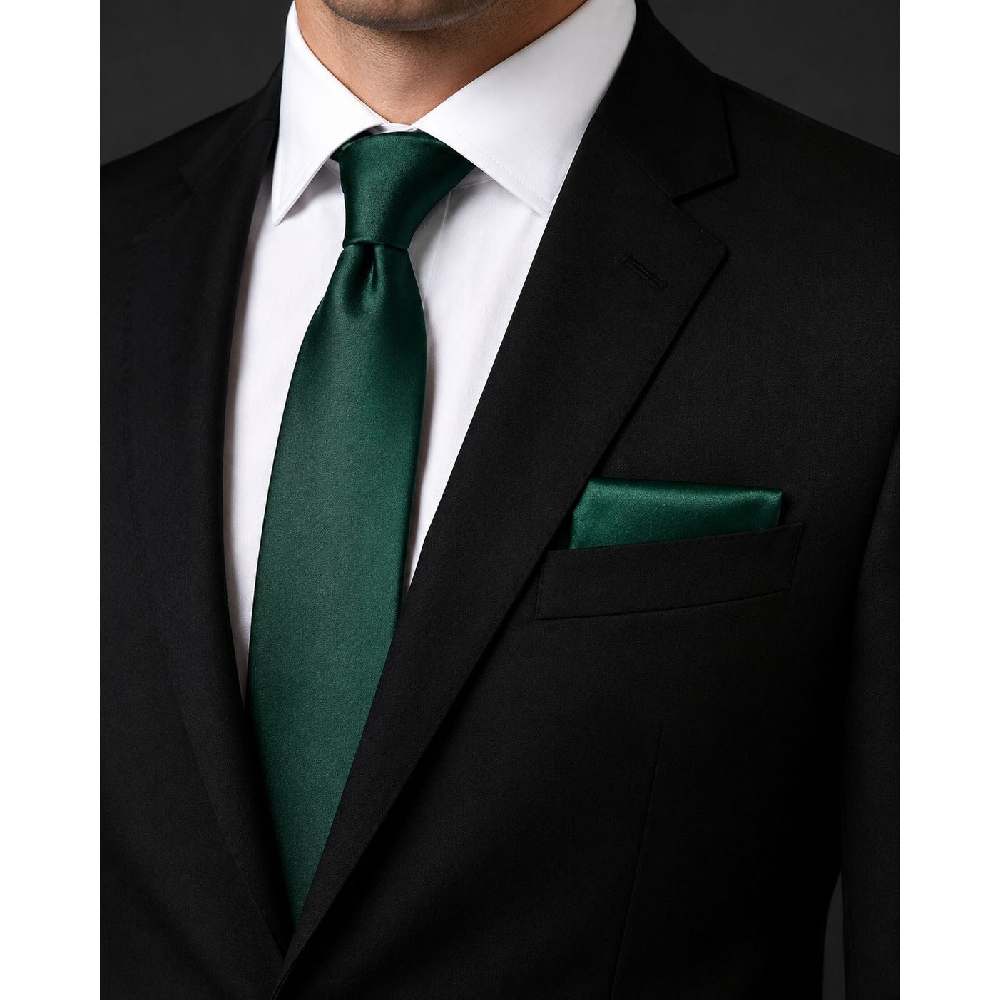 Black suit with a green tie and pocket square on a white background