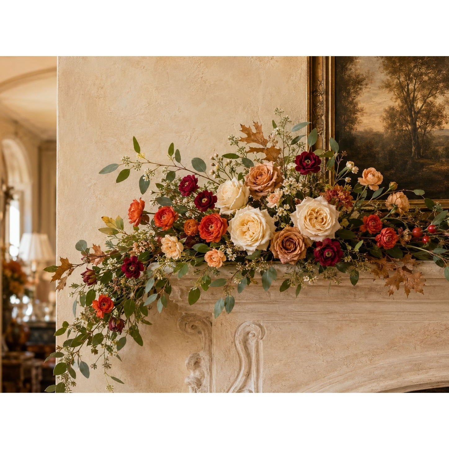 A long floral garland with mixed fall and spring flowers draped across a stone fireplace mantel in an indoor room setting.