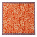 A square silk-like scarf featuring an all-over paisley pattern in orange and beige, finished with a contrasting mauve satin border.