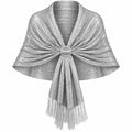 A shimmering silver knit wrap or shawl with fringe and a decorative round center detail, shown on a plain white background.