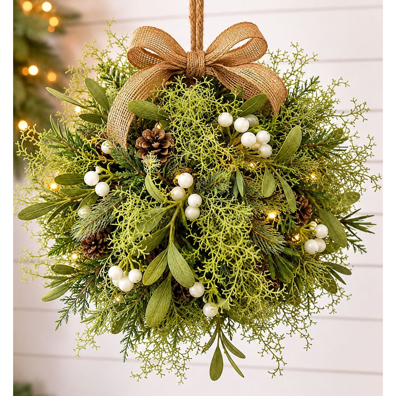 Decorative wreath with greenery, mistletoe, and a brown bow on a white background.
