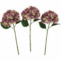 Three artificial hydrangea flowers with pink and green hues on a white background