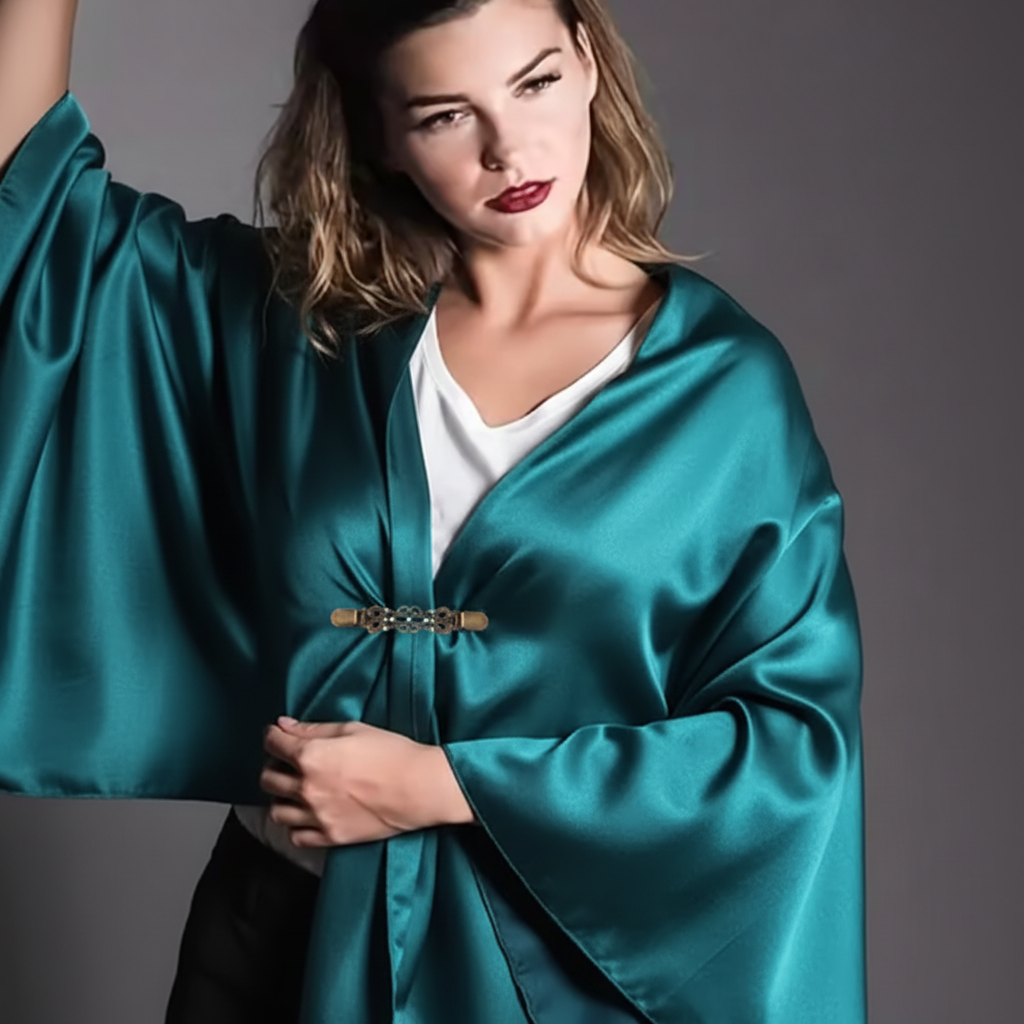 Antiqued bronze sweater clip holding teal satin wild rag scarf as shawl wrap, luxury editorial
