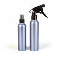 Two metallic blue aluminum bottles side by side on white background, one with black spray trigger cap and one with black pump cap, clean studio hero product shot