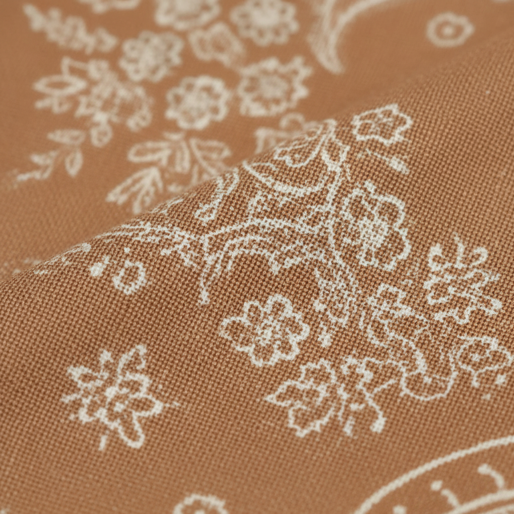 Close-up of tan and cream paisley wild rag scarf fabric texture showing intricate pattern and silk-feel finish