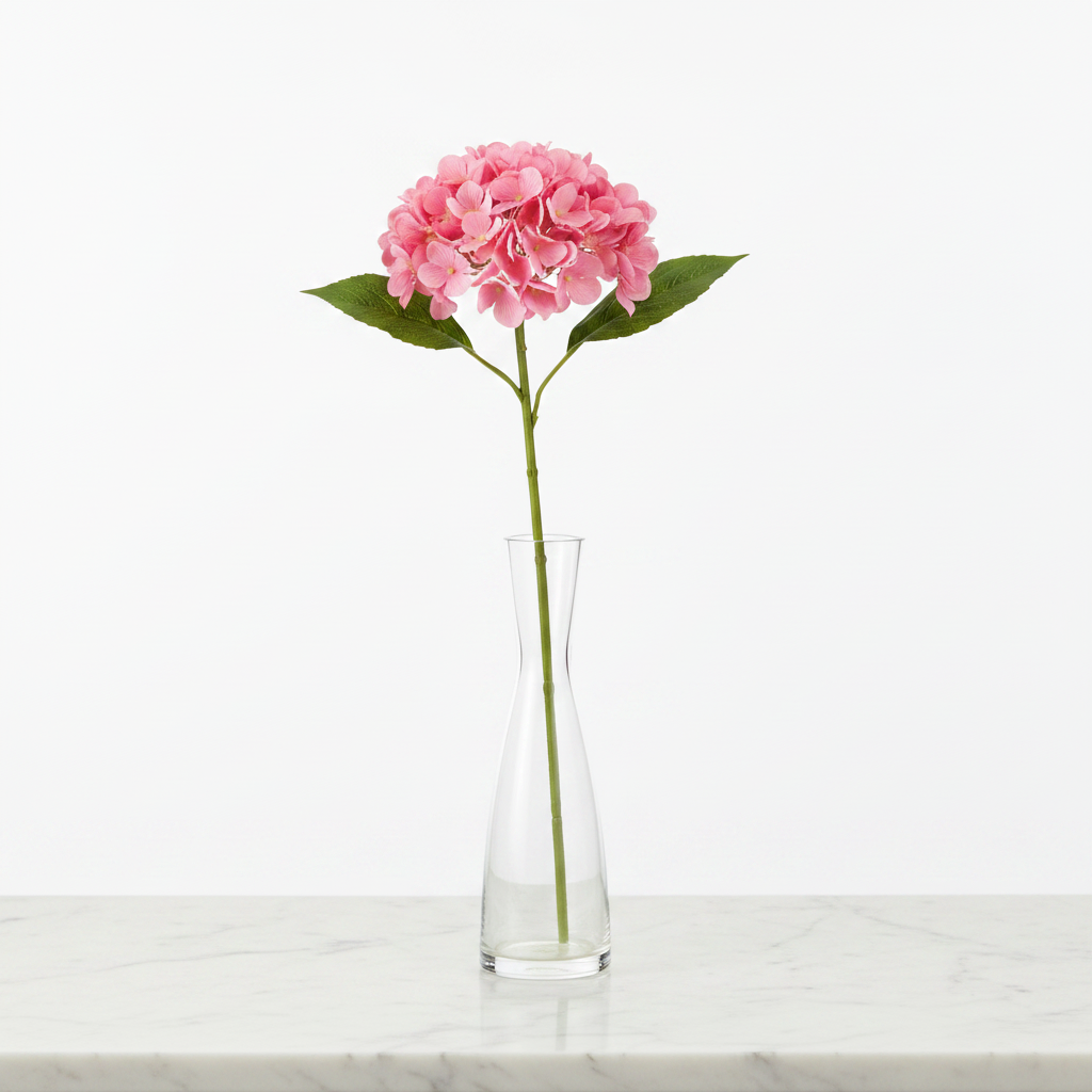 Pink artificial hydrangea stem displayed in clear glass vase on white marble table elegant home decor styling no water