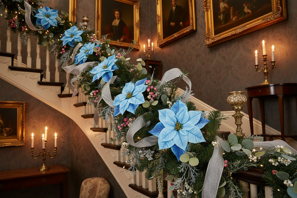 Blue poinsettia bloom heads woven into a lush Victorian Christmas staircase garland with silver ribbon, frosted pine, eucalyptus, and white berry clusters