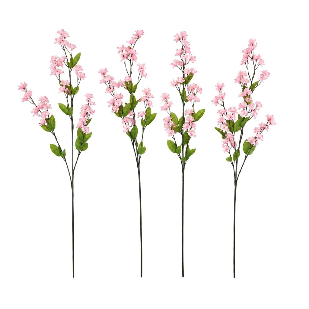 Four artificial pink flowering branches with green leaves and long dark stems, arranged side by side on a plain white background.