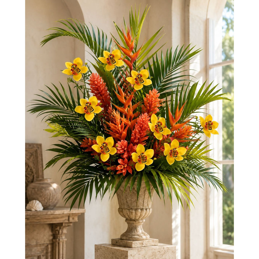 A large tropical flower arrangement in a classical stone urn vase, set on a pedestal in a sunlit interior room with arched windows and columns.