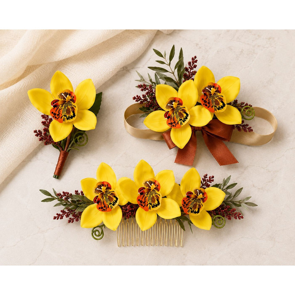 Three floral hair accessories arranged on a light beige fabric background: a wristlet bouquet with yellow orchid-like flowers, a matching hair comb, and a boutonniere. The flowers are bright yellow with dark centers and are accented with green leaves, burgundy sprigs, and a brown ribbon.