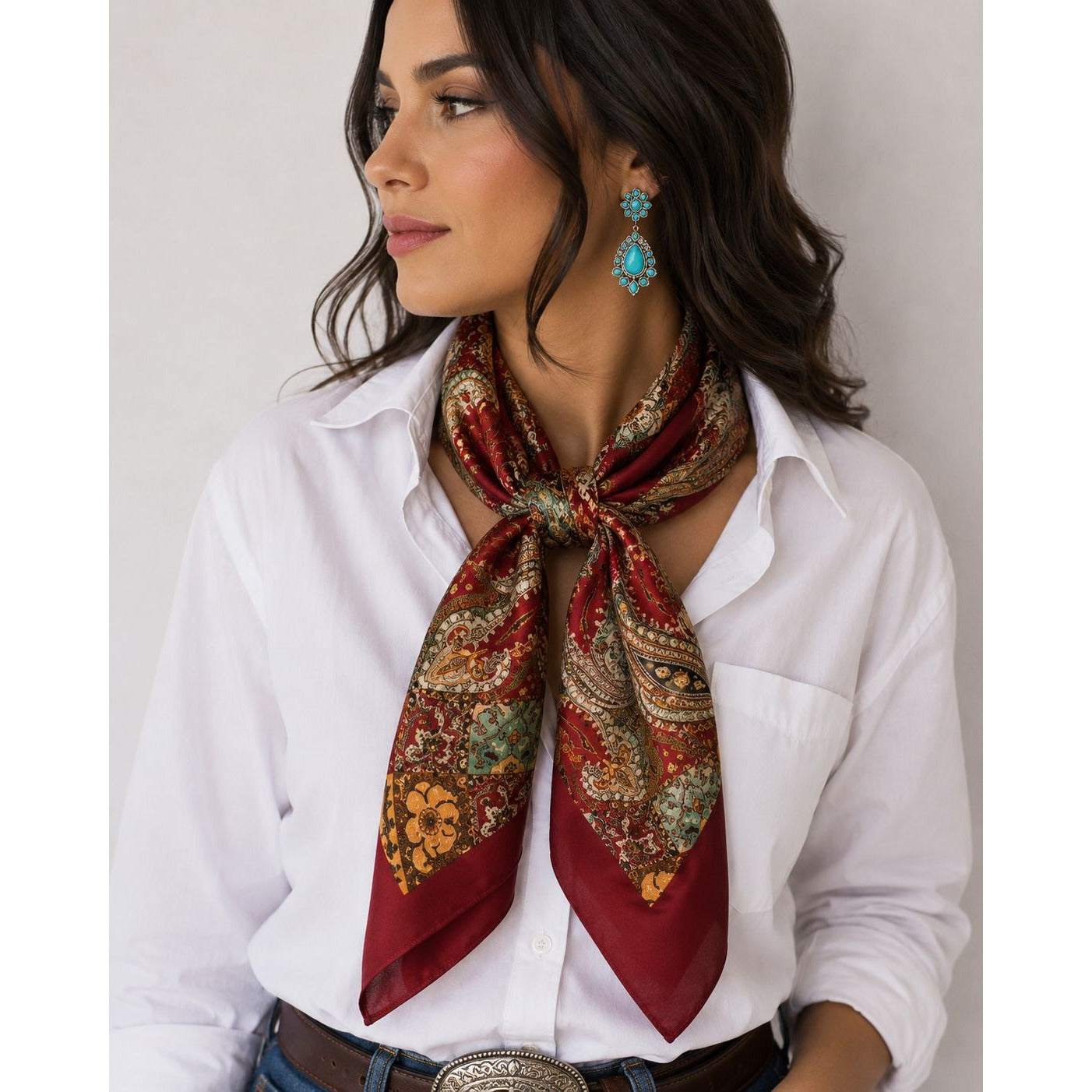 Woman wearing a patterned scarf and turquoise earrings against a neutral background