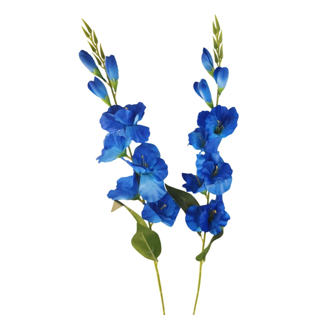 Two artificial blue flower stems with green leaves, photographed against a plain white background.