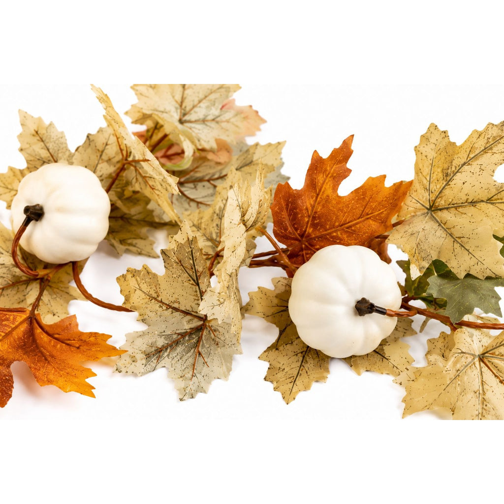 Decorative arrangement of autumn leaves and white pumpkins on a white background