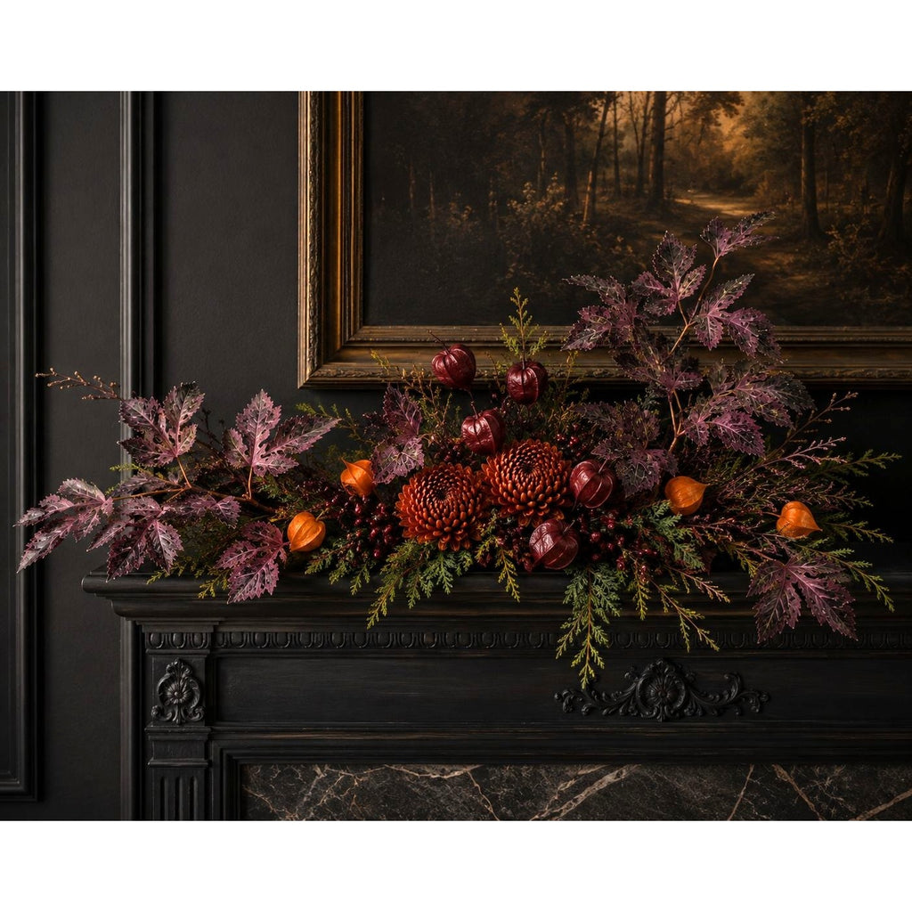 An autumn floral arrangement with burgundy berries, pinecones, small orange pumpkins, and purple foliage, displayed across a dark fireplace mantel beneath a framed forest painting.