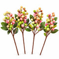 Four artificial berry stems with green leaves, pink and yellow berries, and brown stems, arranged side by side on a white background.