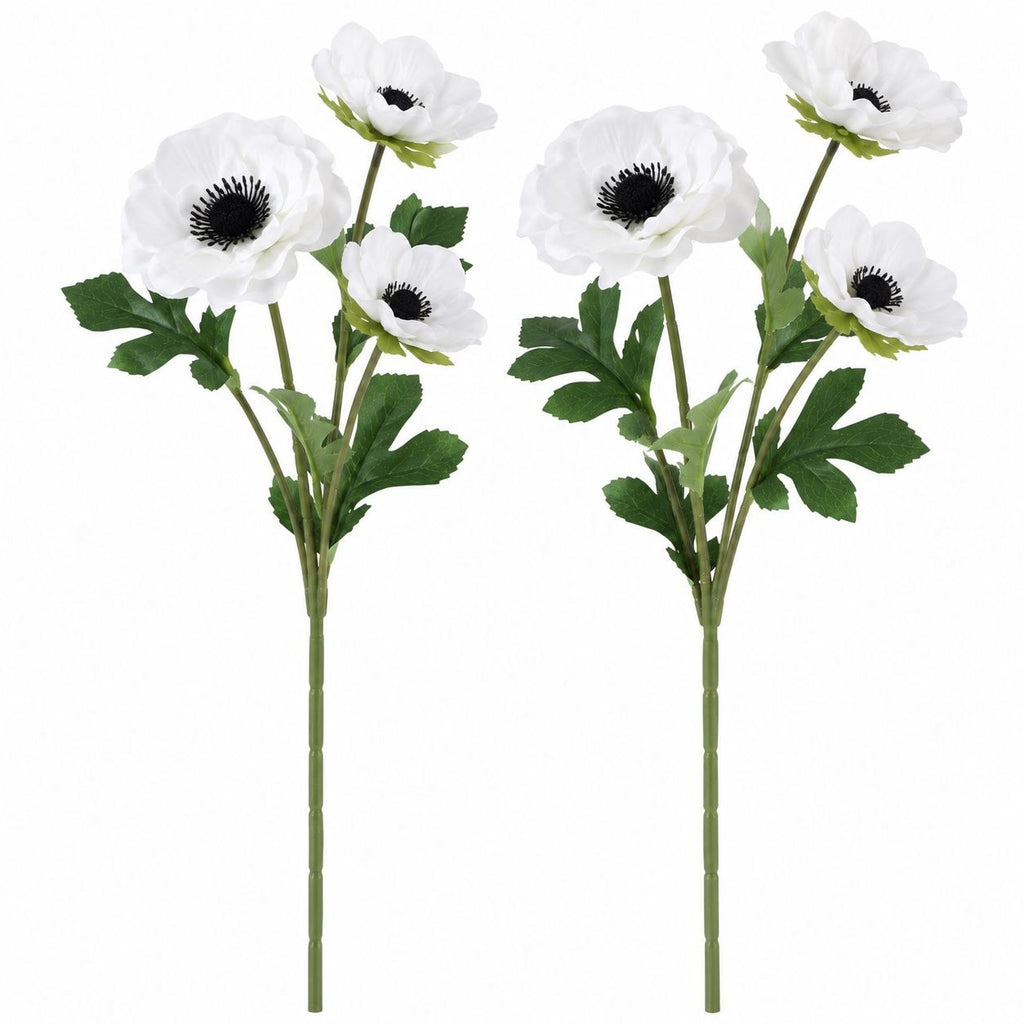 Two artificial anemone flower stems with white petals, dark centers, and green leaves on a plain white background.