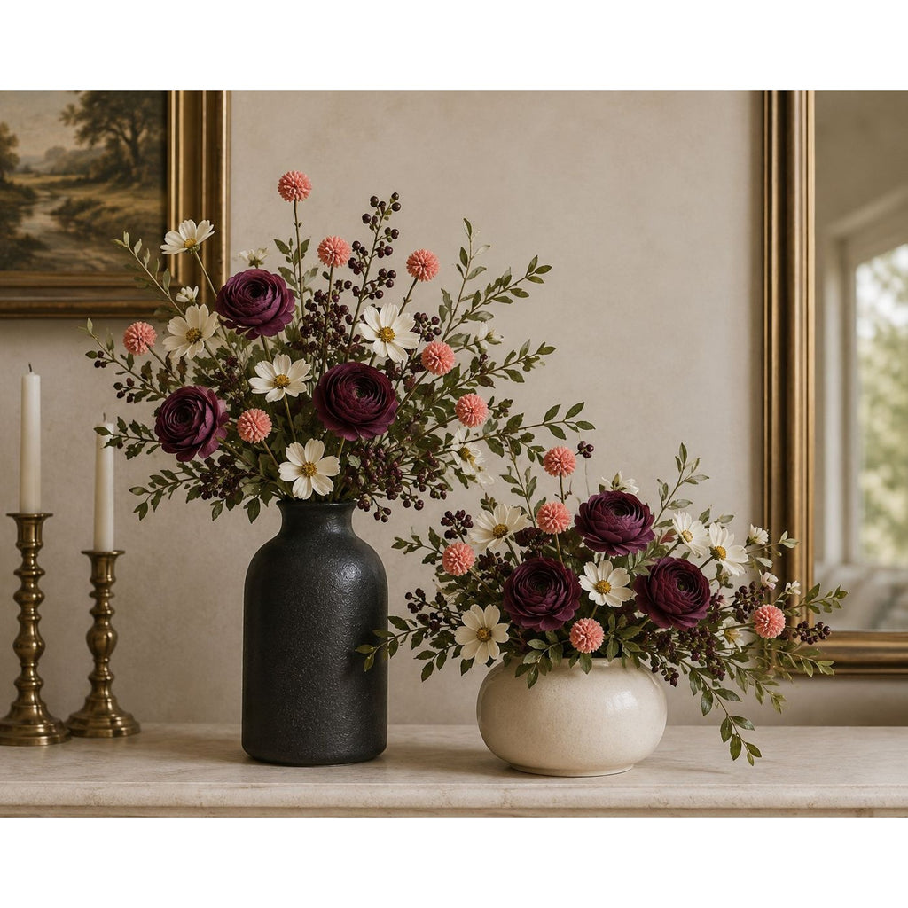 Two floral arrangements displayed on a stone shelf in an interior setting. The larger arrangement sits in a matte black vase, and the smaller arrangement sits in a round off-white vase.