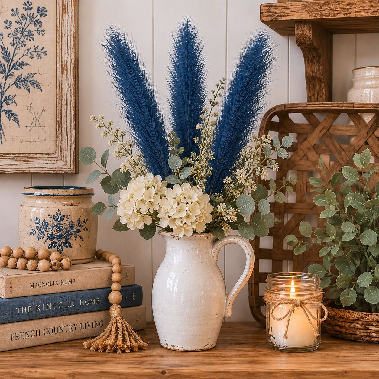 Decorative setup with a vase of flowers, candles, and books on a wooden surface.