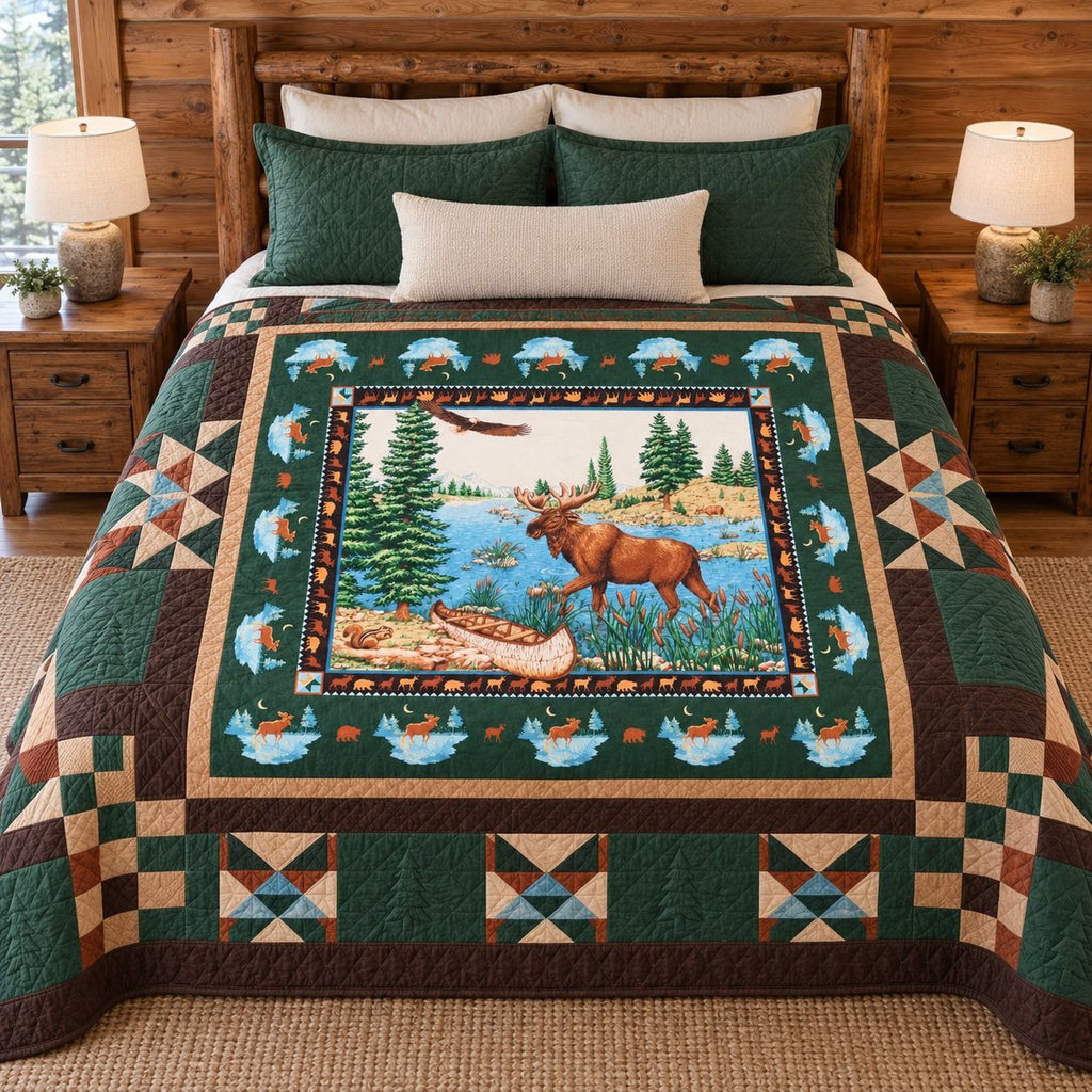 A quilted bedspread with a rustic forest and moose scene in the center, styled on a wooden bed with matching green and cream pillows in a wood-paneled bedroom.