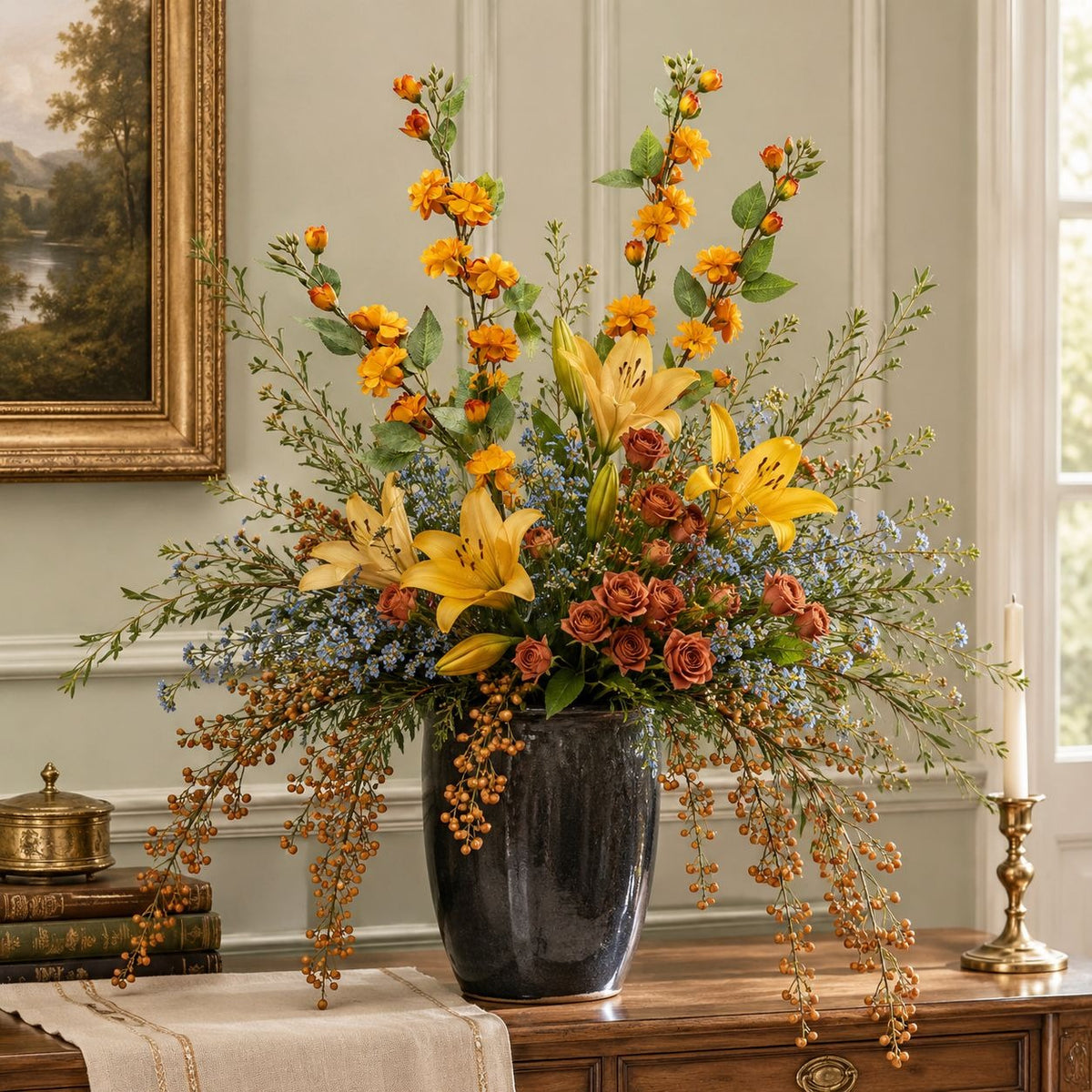 A large artificial floral arrangement in a glossy black vase, featuring yellow lilies, orange flowers, and green foliage, displayed on a wooden console table in a classic room setting.